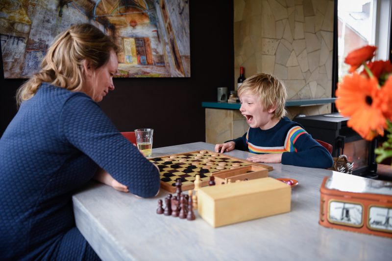 day in the life, familie reportage, bij mensen thuis fotograferen, kind met moeder aan het dammen, fotograaf Assen, natuurlijkliacht fotograaf, fotograaf in Drenthe.